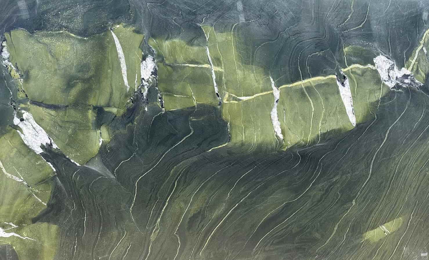 Canlı yeşil ve zeytin tonlarının bir araya geldiği bu mermer, üzerindeki beyaz ve koyu damarlarla doğadan ilham alan dinamik bir görünüm sunar. Özellikle iç mekan tasarımlarında doğal bir vurgu yapmak isteyenler için dikkat çekici bir seçimdir.